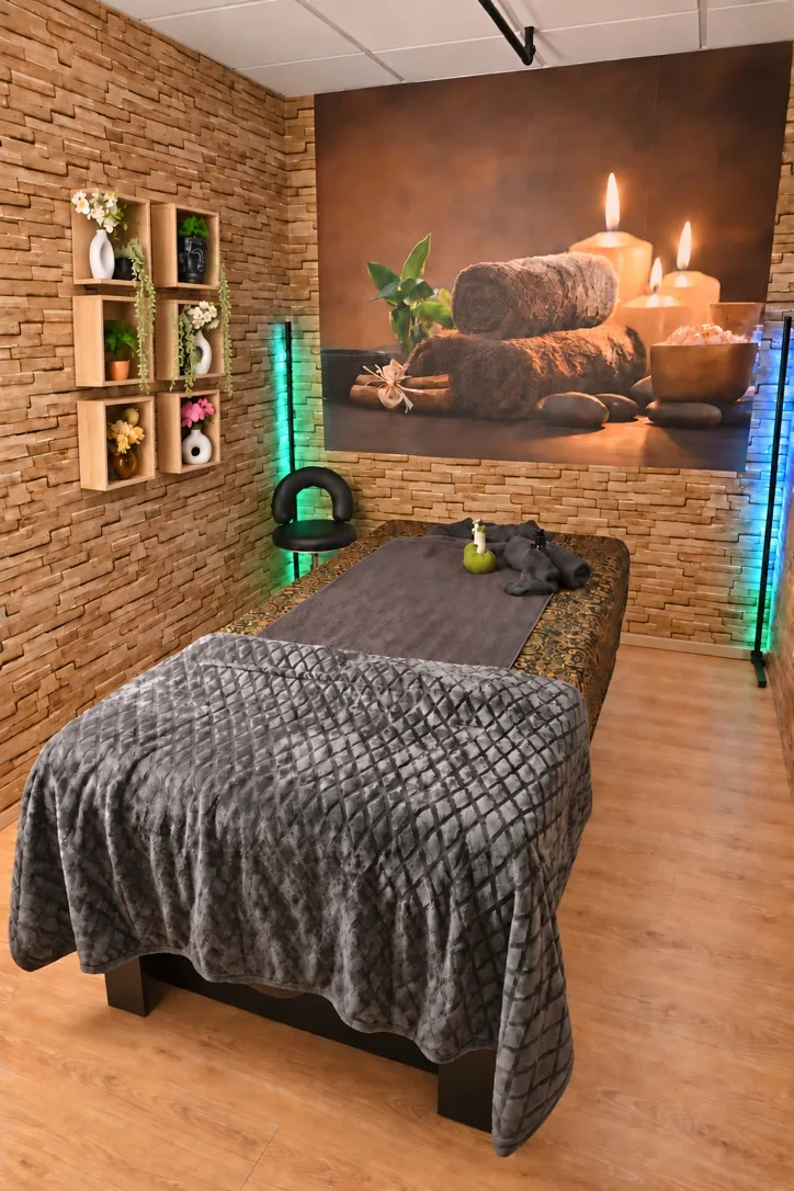 Warme wellness behandelkamer met natuurstenen wand en kaarsdecoratie bij Thao Massage Spa in Hilversum
